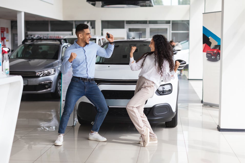 Couple dancing infront of new white SUv at Casa Toyota