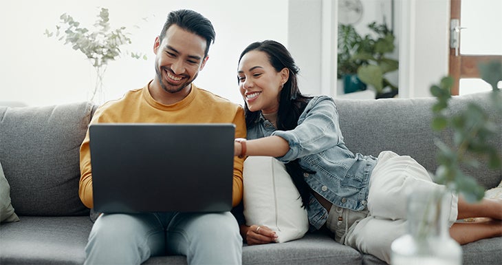 Couple sitting on the sofa customizing their deal on the laptop